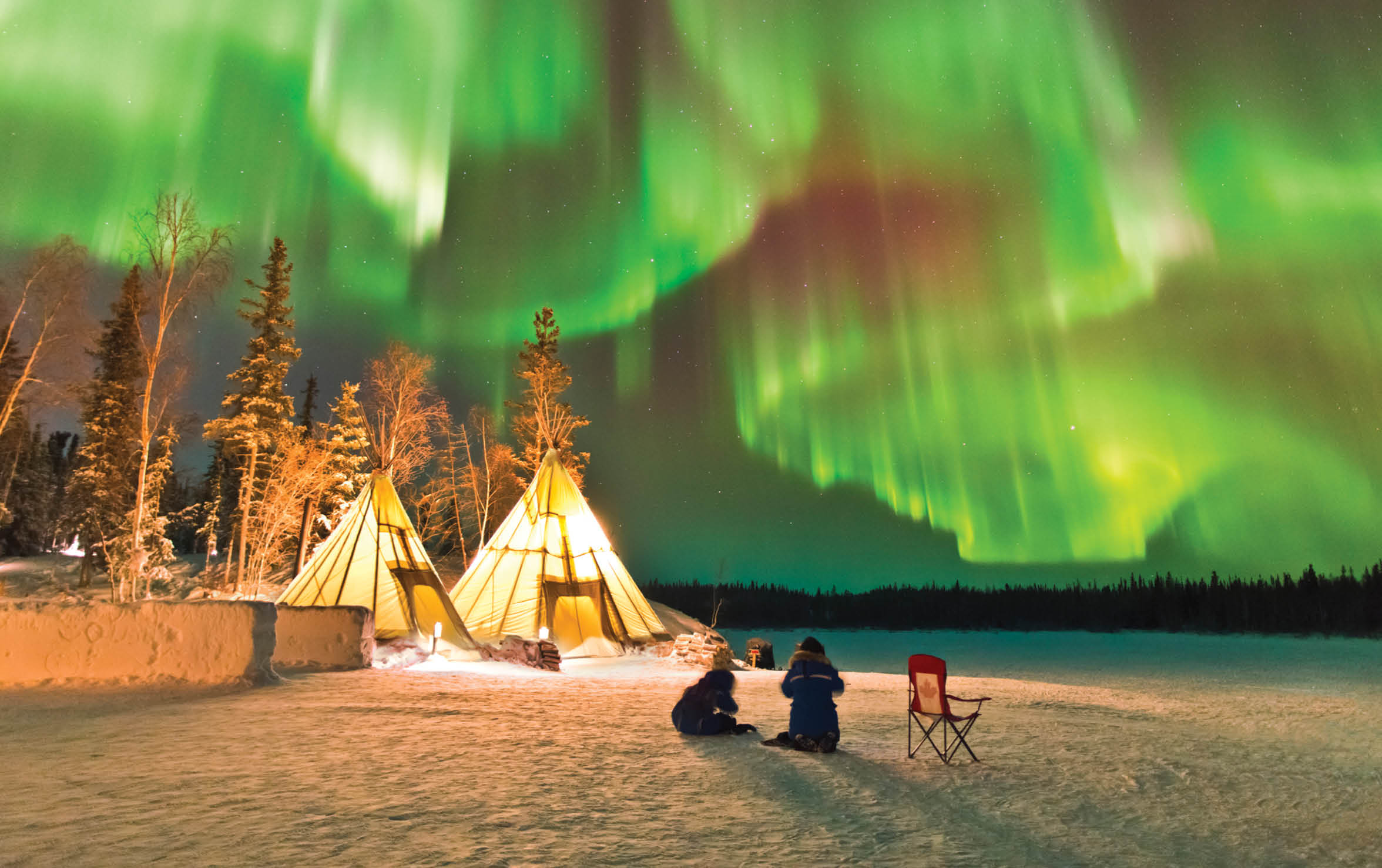 Aurora Village in Yellowknife, Canada is a popular destination to see the Northern Lights up close  The camp s glowing teepees complement the colorful ribbon of lights above 