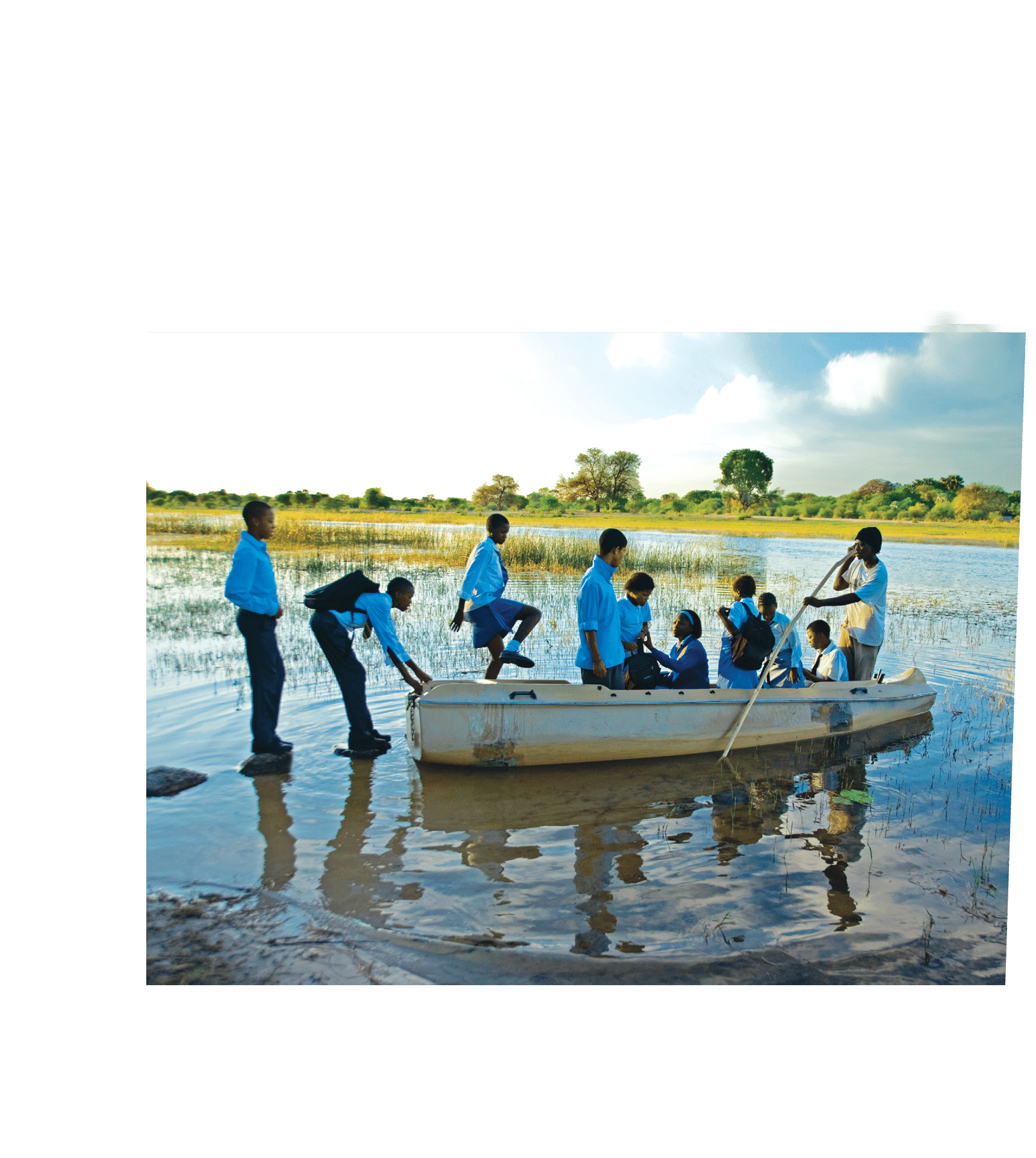 Children cross a river on their way to school in the rainy season 